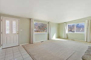 Entrance foyer featuring light tile patterned flooring, visible vents, light colored carpet, and baseboards