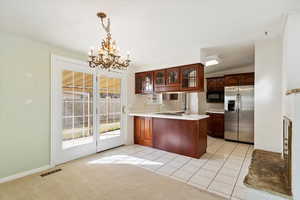 Kitchen with visible vents, a peninsula, stainless steel fridge with ice dispenser, glass insert cabinets, and black microwave