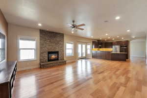 Unfurnished living room featuring recessed lighting, a fireplace, arched walkways, ceiling fan, and light wood-type flooring