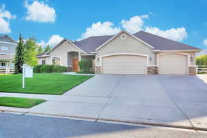 View of front of house featuring stone siding, stucco siding, a garage, and driveway