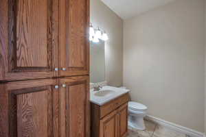 Bathroom featuring tile patterned floors, baseboards, toilet, and vanity