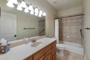 Bathroom featuring tile patterned flooring, visible vents, toilet, shower / bath combination with curtain, and vanity