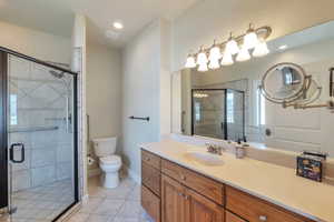 Full bath featuring tile patterned floors, toilet, a shower stall, baseboards, and vanity