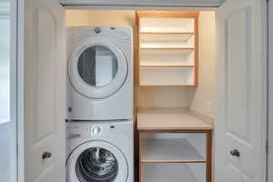 Washroom featuring stacked washer / dryer and laundry area