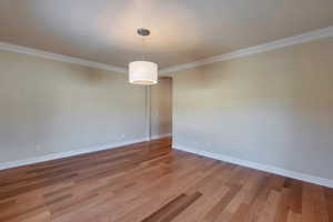 Spare room featuring baseboards, light wood-type flooring, and ornamental molding