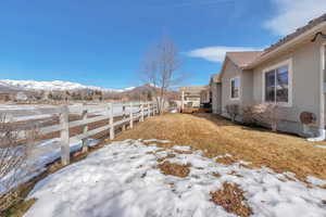 Snowy yard featuring a mountain view and fence