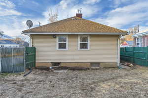 Back of property with a shingled roof, fence, and a chimney