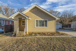 Bungalow with an outbuilding, a front lawn, and fence