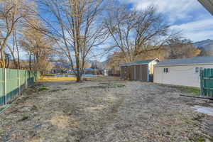 View of yard with a storage shed, an outdoor structure, and fence