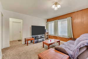 Living room with wooden walls, an inviting chandelier, and carpet