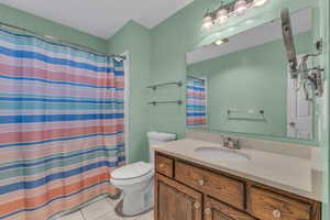 Bathroom featuring tile patterned floors, a shower with shower curtain, toilet, and vanity