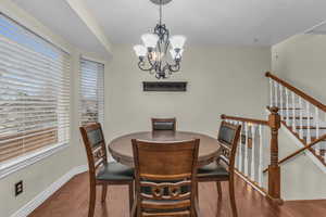 Dining room with stairway, a notable chandelier, wood finished floors, and baseboards