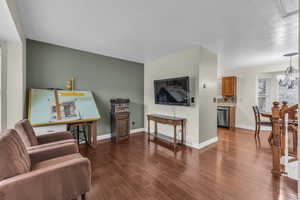 Living room with dark wood finished floors, a chandelier, and baseboards