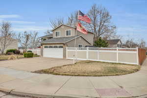 View of home's exterior with brick siding, a shingled roof, fence, concrete driveway, and an attached garage