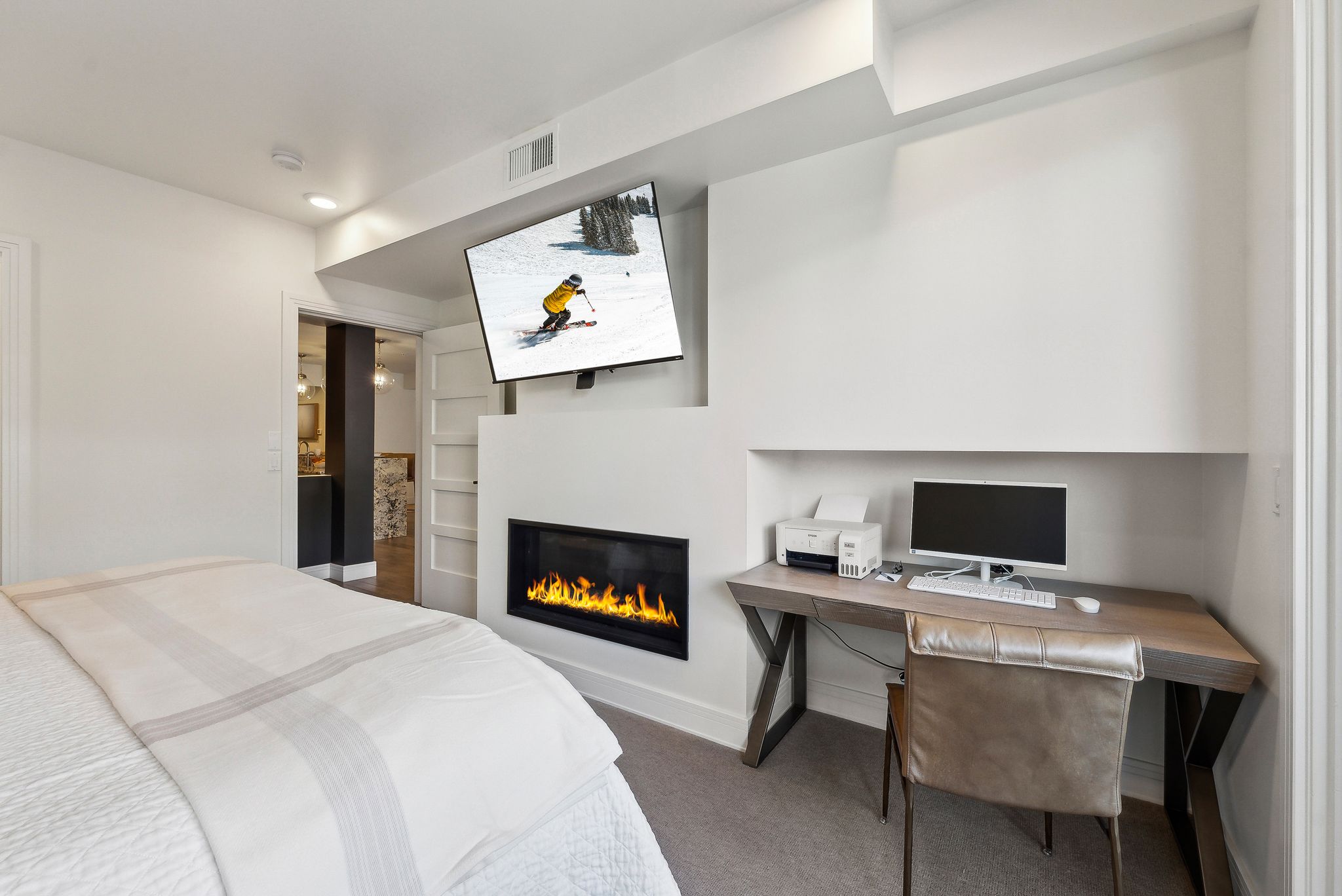 Carpeted bedroom with a glass covered fireplace, baseboards, and visible vents