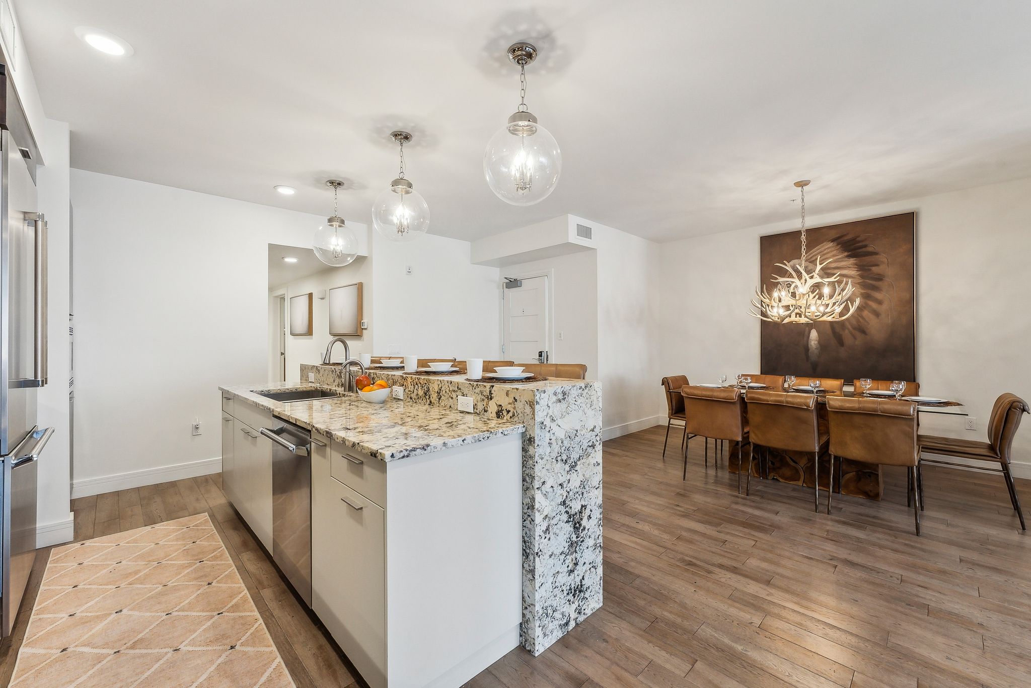 Kitchen with baseboards, a chandelier, dishwasher, light wood-style floors, and a sink
