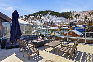 Snow covered patio with a mountain view, an outdoor living space with a fire pit, and a patio