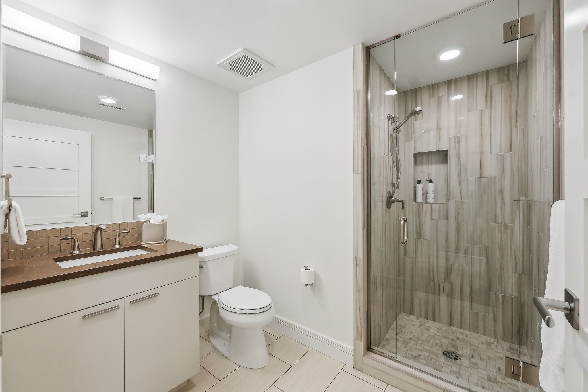 Full bathroom with toilet, visible vents, backsplash, and a stall shower