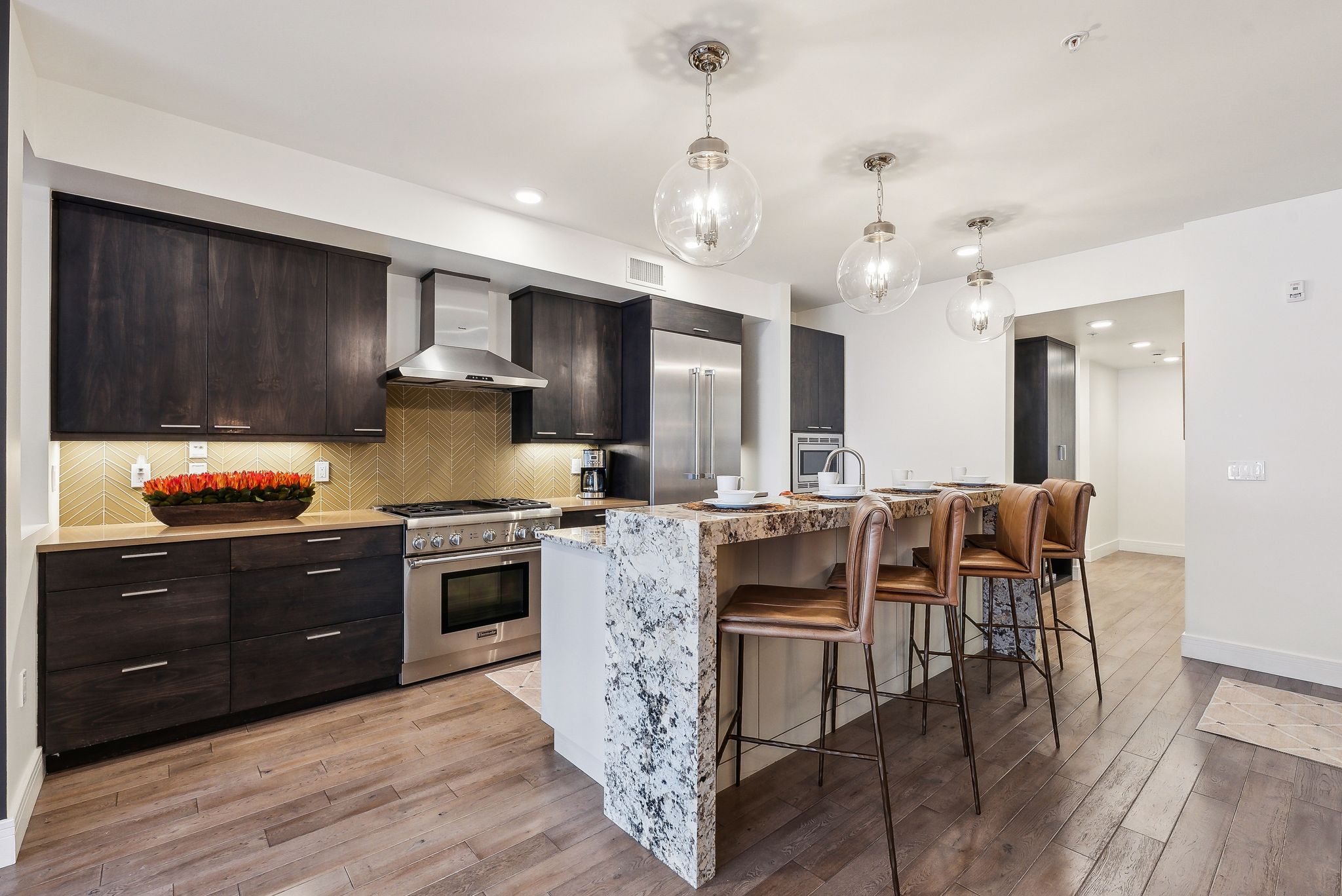 Kitchen featuring decorative backsplash, wall chimney exhaust hood, high quality appliances, and light wood finished floors