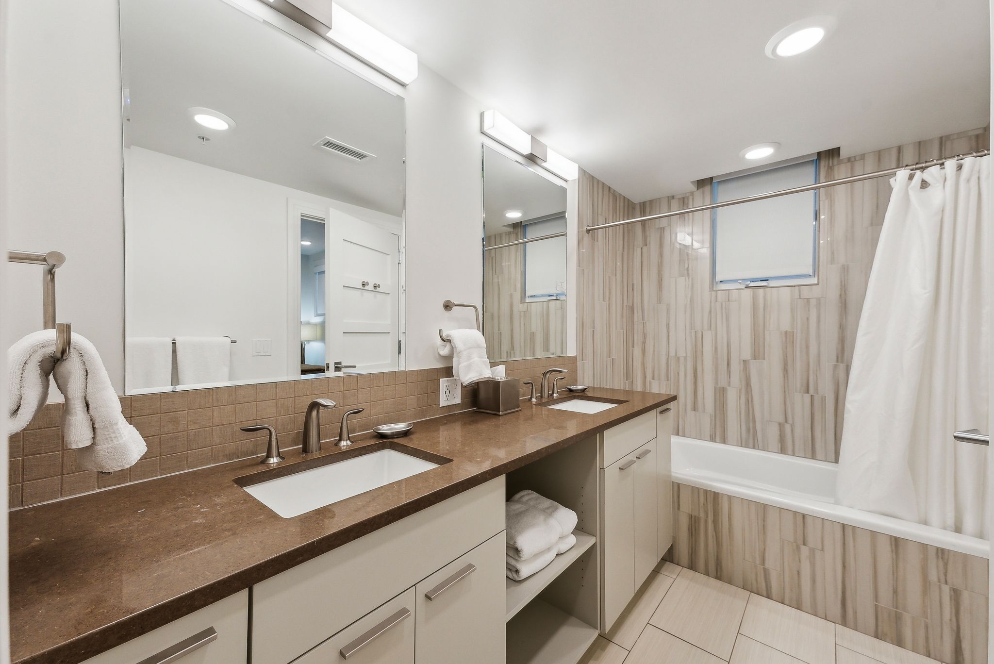 Bathroom with visible vents, tiled shower / bath combo, decorative backsplash, and a sink