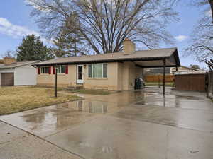 Single story home featuring a chimney, driveway, fence, an attached carport, and brick siding