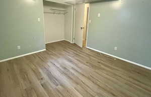 Bedroom with wood finished floors, baseboards, and a closet