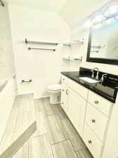 Full bathroom featuring vanity, baseboards, wood tiled floor, lofted ceiling, and toilet