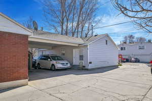 Exterior space featuring entry steps, a carport, driveway, and a shingled roof