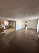 Unfurnished living room featuring a textured ceiling and dark wood-type flooring