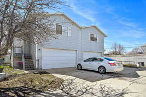 View of front facade featuring driveway, a garage, and fence