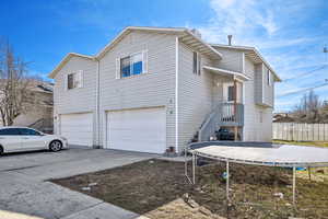 View of property exterior with a garage, a trampoline, concrete driveway, and fence