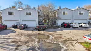 View of front facade featuring central air condition unit, an attached garage, a chimney, and driveway