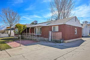 View of front facade featuring brick siding, a shingled roof, and fence