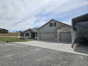 Craftsman-style house featuring concrete driveway, a garage, stone siding, and a front yard