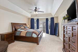 Bedroom with baseboards, ceiling fan, light colored carpet, a tray ceiling, and a textured ceiling