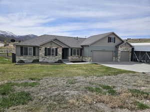 View of front facade with concrete driveway, a garage, a front yard, and stone siding