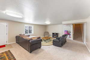 Carpeted living room featuring a textured ceiling, stairs, and baseboards