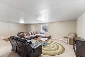 Carpeted living room featuring visible vents, a textured ceiling, and baseboards