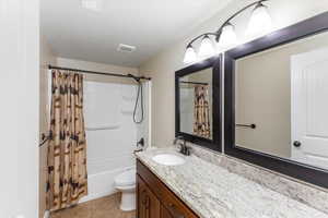Full bath with visible vents, toilet, tile patterned flooring, shower / bath combination with curtain, and vanity