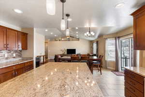 Kitchen featuring tasteful backsplash, open floor plan, pendant lighting, lofted ceiling, and brown cabinets
