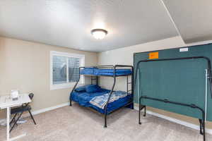 Carpeted bedroom with baseboards and a textured ceiling