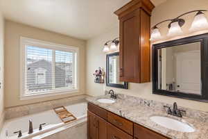 Bathroom with a garden tub, double vanity, and a sink
