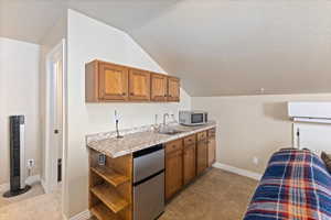 Kitchen featuring brown cabinets, appliances with stainless steel finishes, light countertops, and a sink