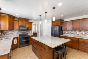 Kitchen with brown cabinetry, double oven range, a sink, black stainless steel microwave, and black stainless fridge