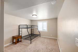 Bedroom with carpet flooring, a textured ceiling, and baseboards
