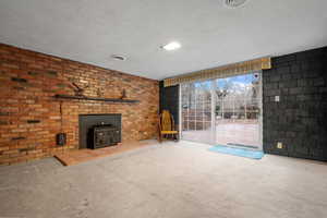 Unfurnished living room featuring carpet flooring, a textured ceiling, visible vents, and a wood stove