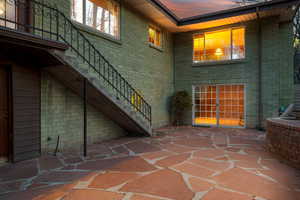 Exterior entry at dusk featuring brick siding and a patio