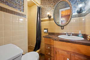 Full bath featuring toilet, tile walls, and a shower stall