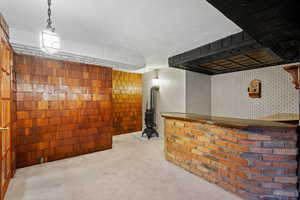 Bar featuring wall chimney range hood, a wood stove, and pendant lighting