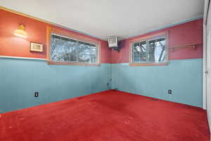 Carpeted spare room featuring visible vents and wainscoting